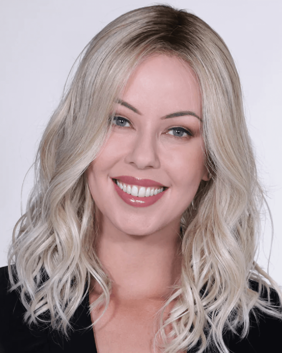 A woman wearing a medium-length, heat-friendly synthetic blonde beach wave wig from BelleTress, showcasing a natural and stylish look.