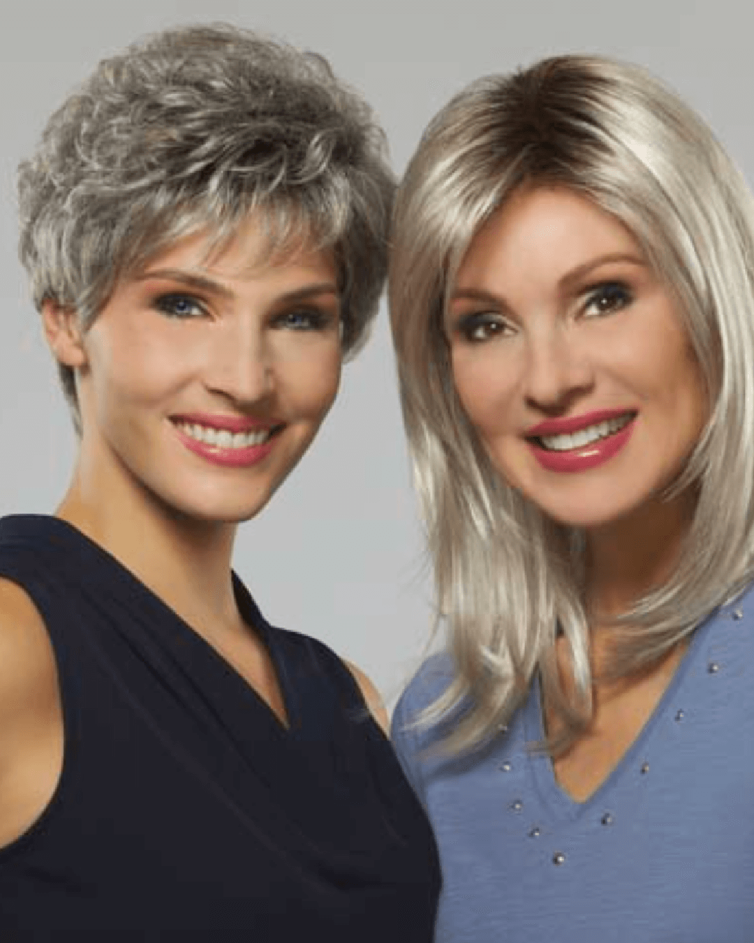 Two women side by side, wearing Henry Margu wigs. One has a short grey wig, the other a longer blonde wig. Both women are smiling, showcasing different styles and colors.