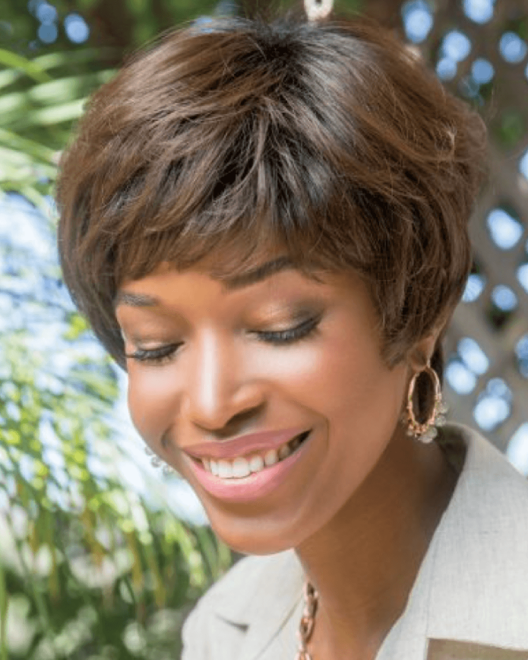 A black woman wearing a short brown pixie wig from the Orchid Collection, showcasing a stylish and confident look.